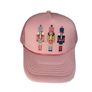 Pink cap with embroidered nutcracker designs on a textured surface